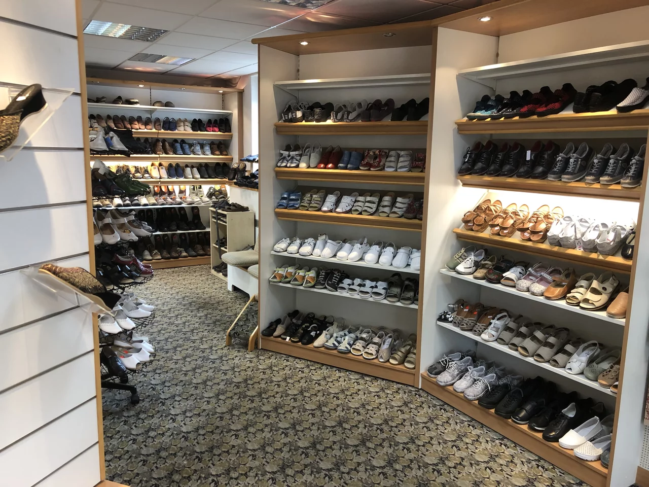 • Abgebildet ist ein Ladengeschäft mit Regalen, in den Auslagen sind verschiedene Schuhe zu sehen.